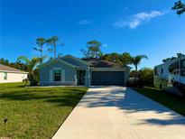 Charming single-story home with a well-manicured lawn and long driveway on a sunny day at 21310 Quesada Ave, Port Charlotte, FL 33952