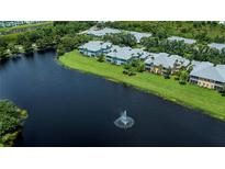 Scenic aerial view of lakeside homes with lush landscaping and a serene fountain, perfect for tranquil living at 25511 Heritage Lake Blvd # 8, Punta Gorda, FL 33983