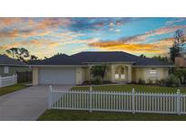 Charming home featuring a lovely lawn, white picket fence, attached garage, and meticulously landscaped front yard at 474 Lomond Dr, Port Charlotte, FL 33953