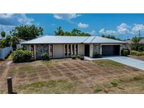 Charming single-story home featuring a metal roof, stone accents, and a convenient attached garage at 543 Mayview Nw Ave, Port Charlotte, FL 33952