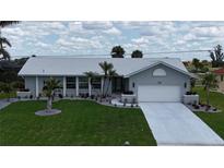 Charming one-story home featuring a well-manicured lawn, mature palm trees and a white tile roof at 745 Monaco Dr, Punta Gorda, FL 33950