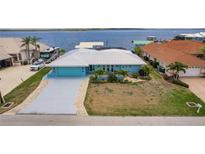 Charming waterfront home featuring a large driveway, turquoise exterior paint and a metal roof and scenic views at 12596 Bacchus Rd, Port Charlotte, FL 33981