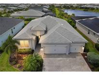 Beautiful aerial view of home, showcasing the three-car garage, paver driveway and landscaping at 17556 Winding Wood Ln, Punta Gorda, FL 33982