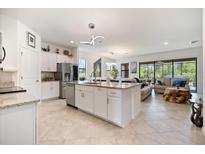 Open-concept kitchen features an island, granite countertops, stainless appliances, and views of the living area at 1993 E Isles Rd, Port Charlotte, FL 33953