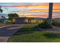 Beautiful sunset illuminates this waterfront property with lush landscaping and a brick paved driveway at 2100 Via Esplanade, Punta Gorda, FL 33950