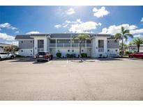 Condominium building featuring a well-maintained exterior, ample parking, and lush landscaping with palm trees under a bright sky at 22375 Edgewater Dr # 123, Punta Gorda, FL 33980