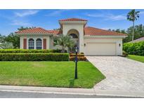 Charming single-story home with a red tile roof, manicured lawn, and beautiful landscaping at 3050 Rivershore Ln, Port Charlotte, FL 33953