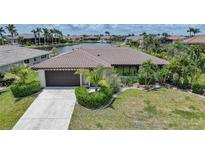 Charming single-story home with a tile roof, lush landscaping, and waterfront views at 376 Portofino Dr, Punta Gorda, FL 33950