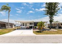 Charming single-story home with a covered carport, lush trees, and a well-manicured lawn at 713 Riverview Cir, North Port, FL 34287