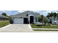 Charming single-story home with well-manicured lawn, black door, and attached garage at 10068 Winding River Rd, Punta Gorda, FL 33950