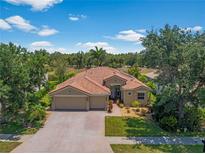 Beautiful home with a tile roof, a three car garage and mature landscaping at 11982 Granite Woods Loop, Venice, FL 34292