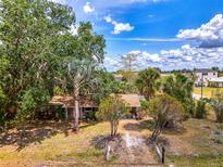 Charming home featuring mature trees, a brick facade, and a cozy front porch at 12018 Saragossa Ln, North Port, FL 34287