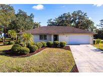 Charming single-story home featuring a well-manicured lawn, neat landscaping, and an attached two-car garage at 14534 Keene Ave, Port Charlotte, FL 33953
