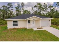 Charming single-story home featuring a well-manicured lawn and attached one car garage in a wooded area at 27456 Corinthian Dr, Punta Gorda, FL 33955
