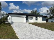 Charming single-story home features a spacious two-car garage and beautifully patterned brick driveway at 3045 Montgomery Dr, Port Charlotte, FL 33981