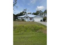Charming single-story home with a well-maintained lawn, attached garage, and a serene, tree-lined backdrop at 4395 Abcor Rd, North Port, FL 34286