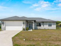 Charming single-story home featuring a two-car garage, neutral colors, and a well-manicured lawn at 97 Pine Valley Ln, Rotonda West, FL 33947