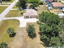 An aerial view of a single story home, with long driveway and mature trees on a sunny day at 10112 Willmington Blvd, Englewood, FL 34224