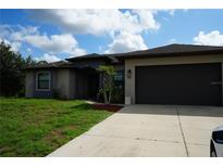Beautiful one-story home featuring a gray stucco exterior, a driveway, and manicured lawn at 1480 Wise Dr, North Port, FL 34286