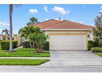 Charming single-story home with a two-car garage, tropical landscaping, and a red tile roof at 181 Padova Way # 19, Nokomis, FL 34275