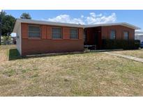 Single story home with a brick facade and orange shutters sitting on a large lawn at 2328 Picnic St, Port Charlotte, FL 33952