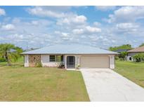 Charming single-story home featuring a clean driveway, neutral paint and a sturdy metal roof at 27050 Pelotas Dr, Punta Gorda, FL 33983