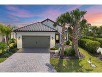 Charming single-story home with a two-car garage, a brick driveway, and lush tropical landscaping at 281 Potenza Loop, Nokomis, FL 34275