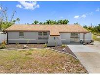 Charming single-story home with gray exterior, brown roof and manicured front lawn at 10517 Greenway Ave, Englewood, FL 34224