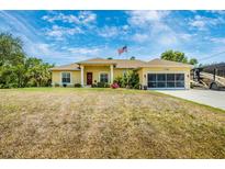 Charming yellow home featuring an American flag, well-maintained landscaping, and attached garage at 13325 Ketridge Ave, Port Charlotte, FL 33953