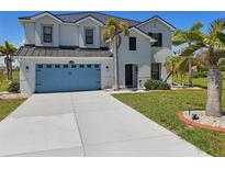 Beautiful two story home featuring a light blue garage door, stucco exterior and mature tropical landscaping at 17304 Vagabond Cir, Punta Gorda, FL 33955