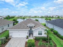 Beautiful single-story home with lush landscaping and lake view, featuring a two-car garage and brick-paved driveway at 17620 Winding Wood Ln, Punta Gorda, FL 33982