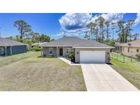 Beautiful single-story home features a gray exterior, well-maintained lawn, and an attached two-car garage at 18503 Ellen Ave, Port Charlotte, FL 33948