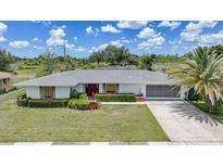 Charming single-story home featuring a well-manicured lawn, tropical landscaping, and an attached two-car garage at 2193 Beacon Dr, Port Charlotte, FL 33952