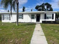 Charming single-story home with a well-manicured lawn and a walkway leading to the front door at 230 Waterway Cir Ne, Port Charlotte, FL 33952