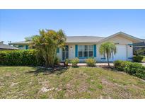 Charming single-story home featuring lush landscaping, turquoise shutters, and a well-maintained lawn at 25449 Doredo Dr, Punta Gorda, FL 33955