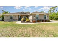 Charming single-story home boasts a well-manicured lawn, stone accents, and inviting curb appeal at 2707 Auburn Blvd, Port Charlotte, FL 33948