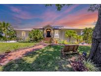 Charming home with a lush front yard, brick walkway, mature trees and manicured landscaping at 6242 Tropicaire Blvd, North Port, FL 34291