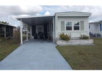 Cozy mobile home featuring a covered parking area and a well-maintained lawn at 6832 Holo Ct, North Port, FL 34287