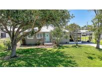 Charming home featuring a lush green lawn, mature trees, and a quaint entrance with a light blue door at 809 Kings Ct, Punta Gorda, FL 33950