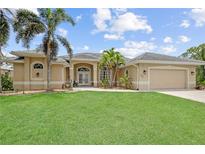 Charming home with lush green lawn, tropical palms, and a neutral color scheme at 13297 Flaherty Ave, Port Charlotte, FL 33981