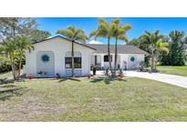 Charming single-story home featuring a well-manicured lawn and beautiful palm trees enhancing its curb appeal at 16615 Acapulco Rd, Punta Gorda, FL 33955