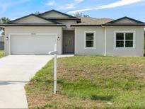 Charming single-Gathering home with a two-car garage and well-manicured lawn on a sunny day at 19092 Woodbine Ave, Port Charlotte, FL 33954