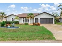 Charming single-story home with well-manicured lawn and tropical landscaping, enhancing curb appeal at 26177 Madras Ct, Punta Gorda, FL 33983