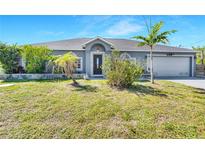 Charming single-story home featuring a well-manicured lawn and tropical landscaping, offering curb appeal at 9295 Melody Cir, Port Charlotte, FL 33981