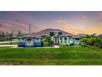 Stunning exterior with lush lawn, mature landscaping and striking architectural details at sunset at 10233 St Paul Dr, Port Charlotte, FL 33981