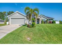 Charming single-story home featuring stone accents, a well-manicured lawn, and a two-car garage, with a palm tree in the front yard at 1321 Calgary Rd, North Port, FL 34288
