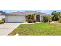 Charming single-story home featuring a metal roof, two-car garage, and a beautifully landscaped front yard at 17368 Skipper Ln, Port Charlotte, FL 33948