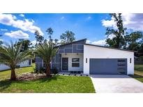 Modern home with stylish gray and white facade, landscaped front yard, and attached two car garage at 19160 Ruskin Ave, Port Charlotte, FL 33954