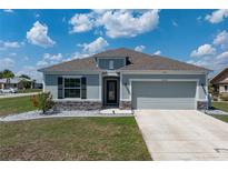 Charming single-story home with gray stucco, well-manicured lawn, stone accents, and a two-car garage at 25308 Rupert Rd, Punta Gorda, FL 33983