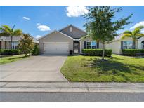Charming one-story home with a well-manicured lawn, a two-car garage, and lush landscaping under a partly cloudy sky at 25312 E Lenox Cir, Punta Gorda, FL 33950